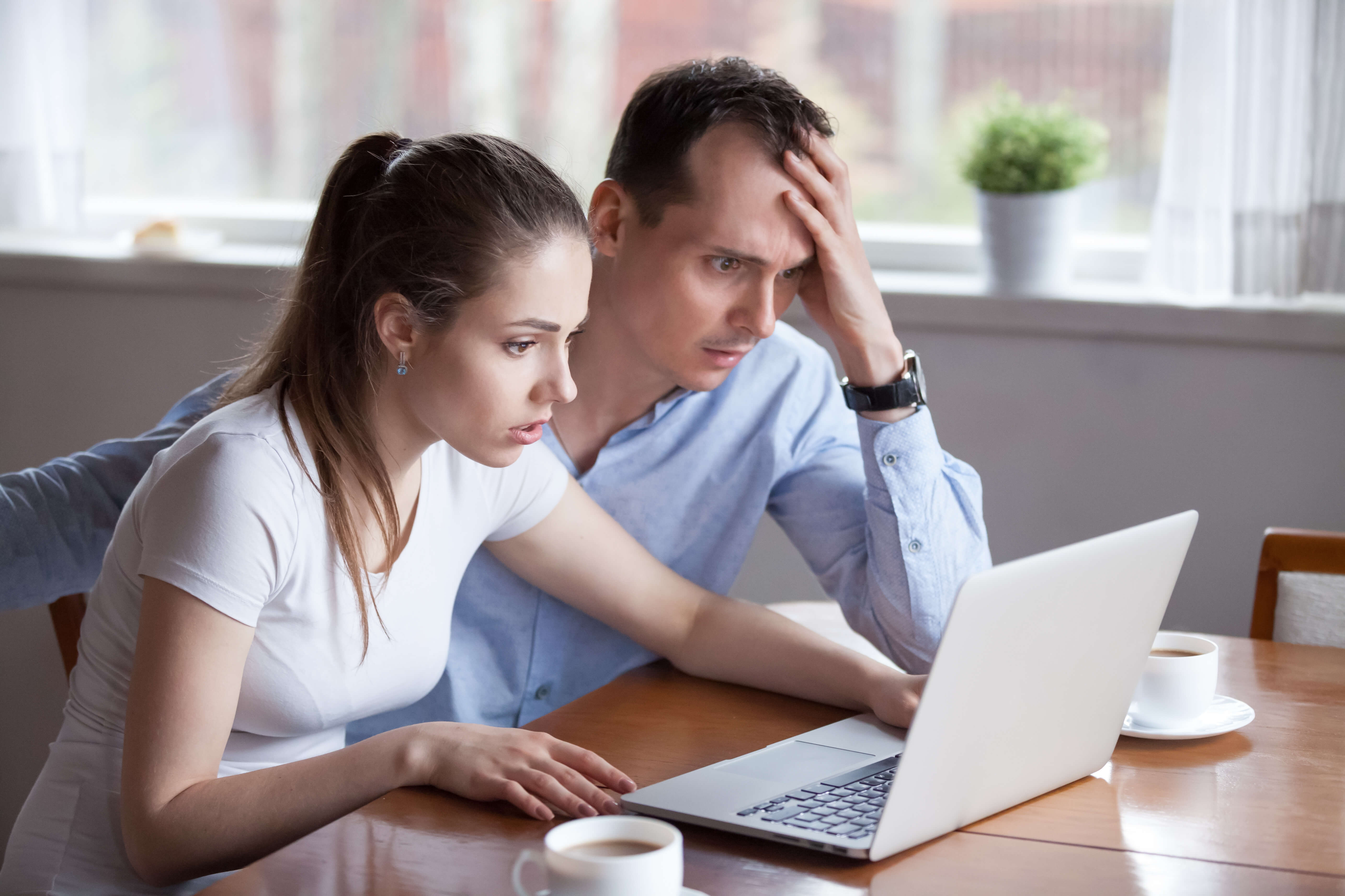 couple looking at laptop astonished